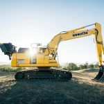 a yellow excavator sitting on top of a dirt field