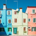 Vibrant blue, green, and pink houses against a clear sky.