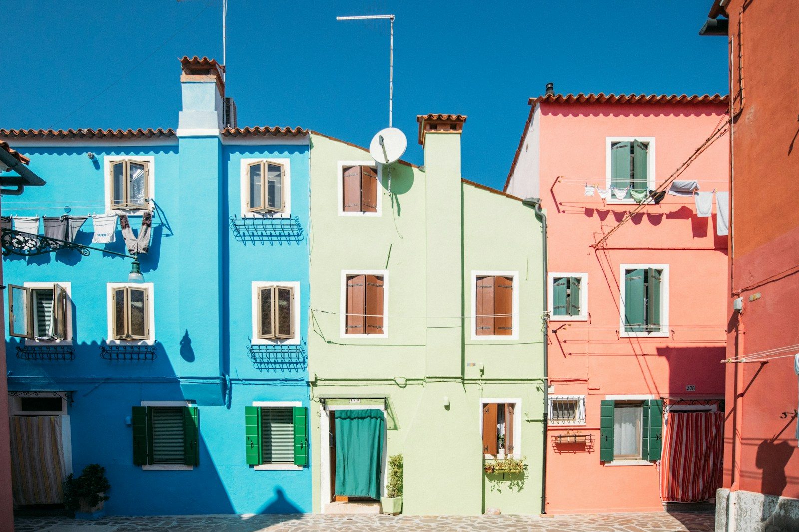 Vibrant blue, green, and pink houses against a clear sky.
